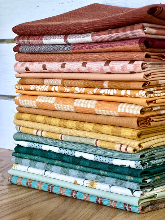 Stack of folded fabric swatches in various colors on a wooden surface