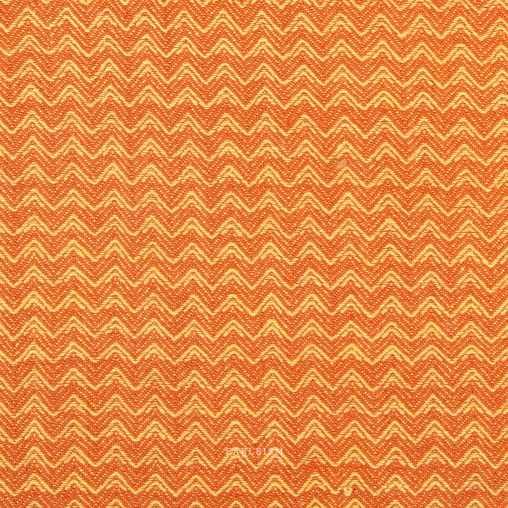 A close-up of a woven fabric with a repeating chevron pattern in orange and cream.