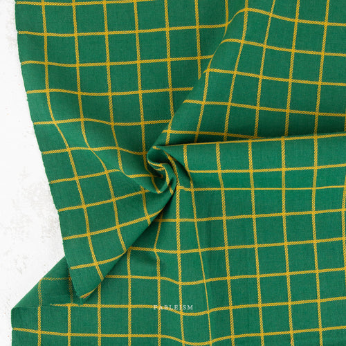 Green fabric with a yellow grid pattern, draped to show its texture and weave.