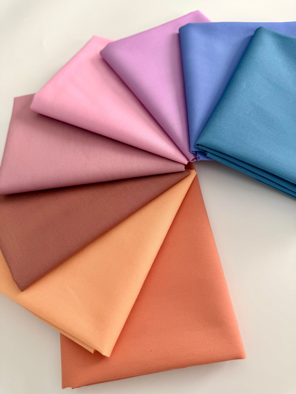 Fabric swatches in various colors arranged in a circular pattern on a light background