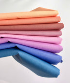 Stack of colorful fabric swatches in various shades on a white background