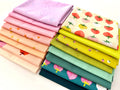A bright, overhead shot of sixteen overlapping folded fabric pieces. Features a gradient of lavender, bubblegum pink, and peach fabrics with star and strawberry prints, a large-scale strawberry print on cream, transitioning into zesty lime greens, mint, and deep teal fabrics with pink strawberry motifs. The entire collection is displayed against a clean white background.