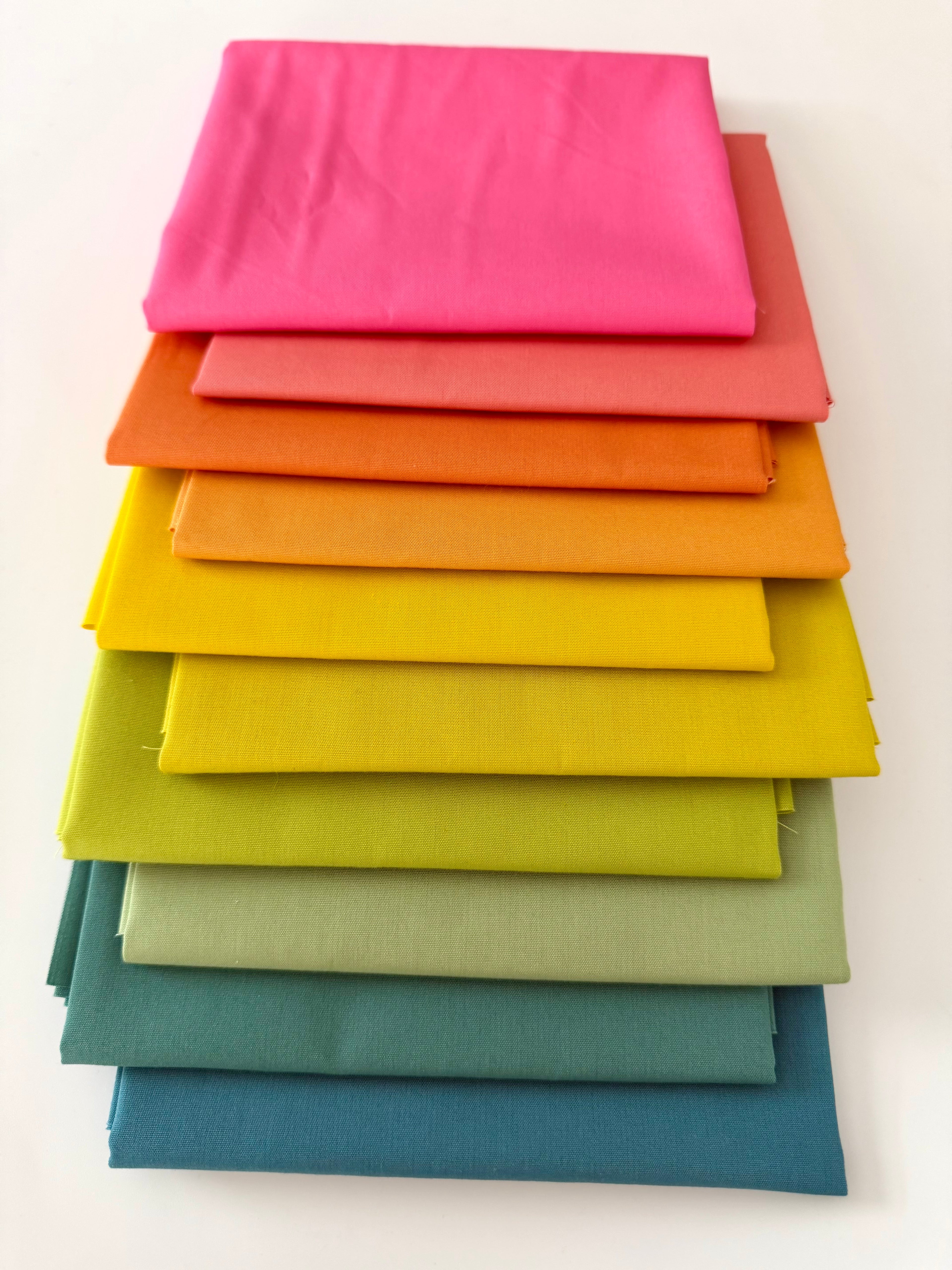 Stack of colorful fabric swatches in various shades on a white background