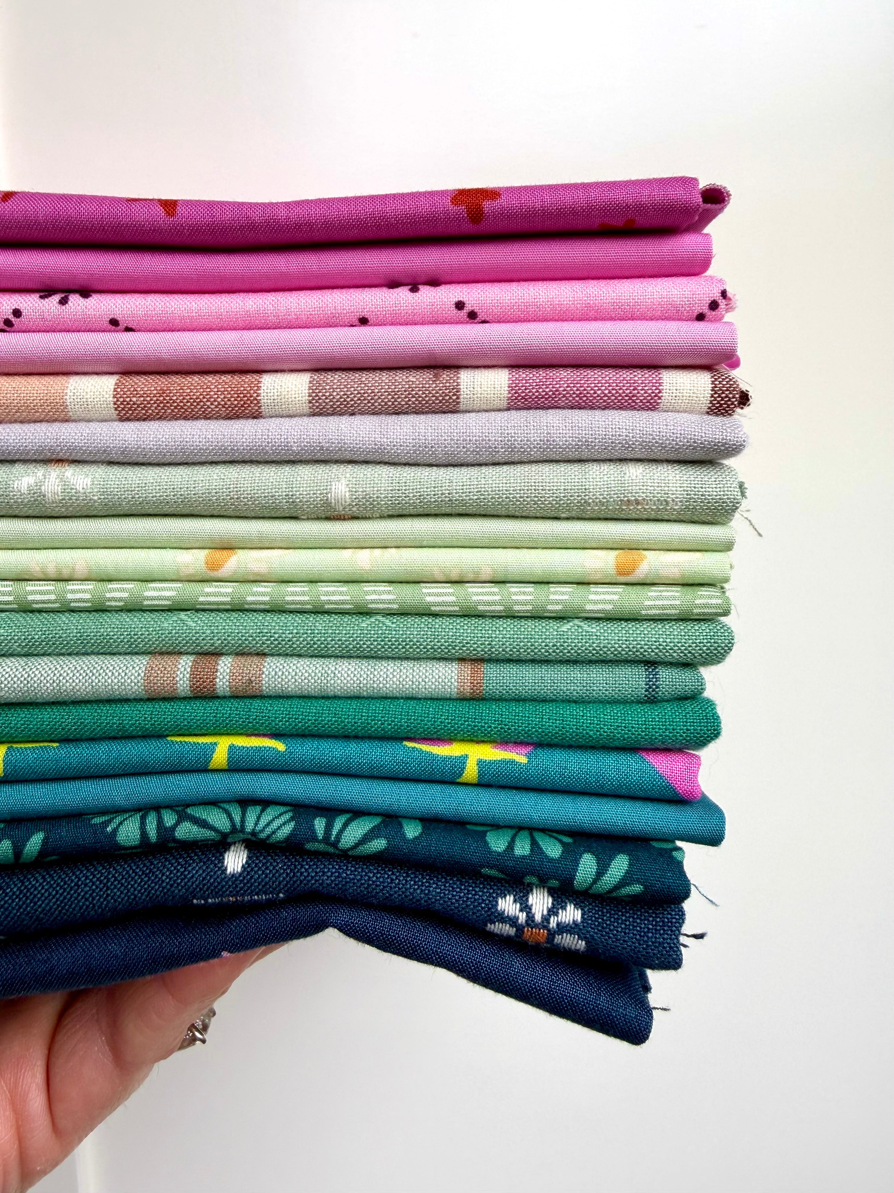Stack of colorful fabric swatches held by a hand against a white background