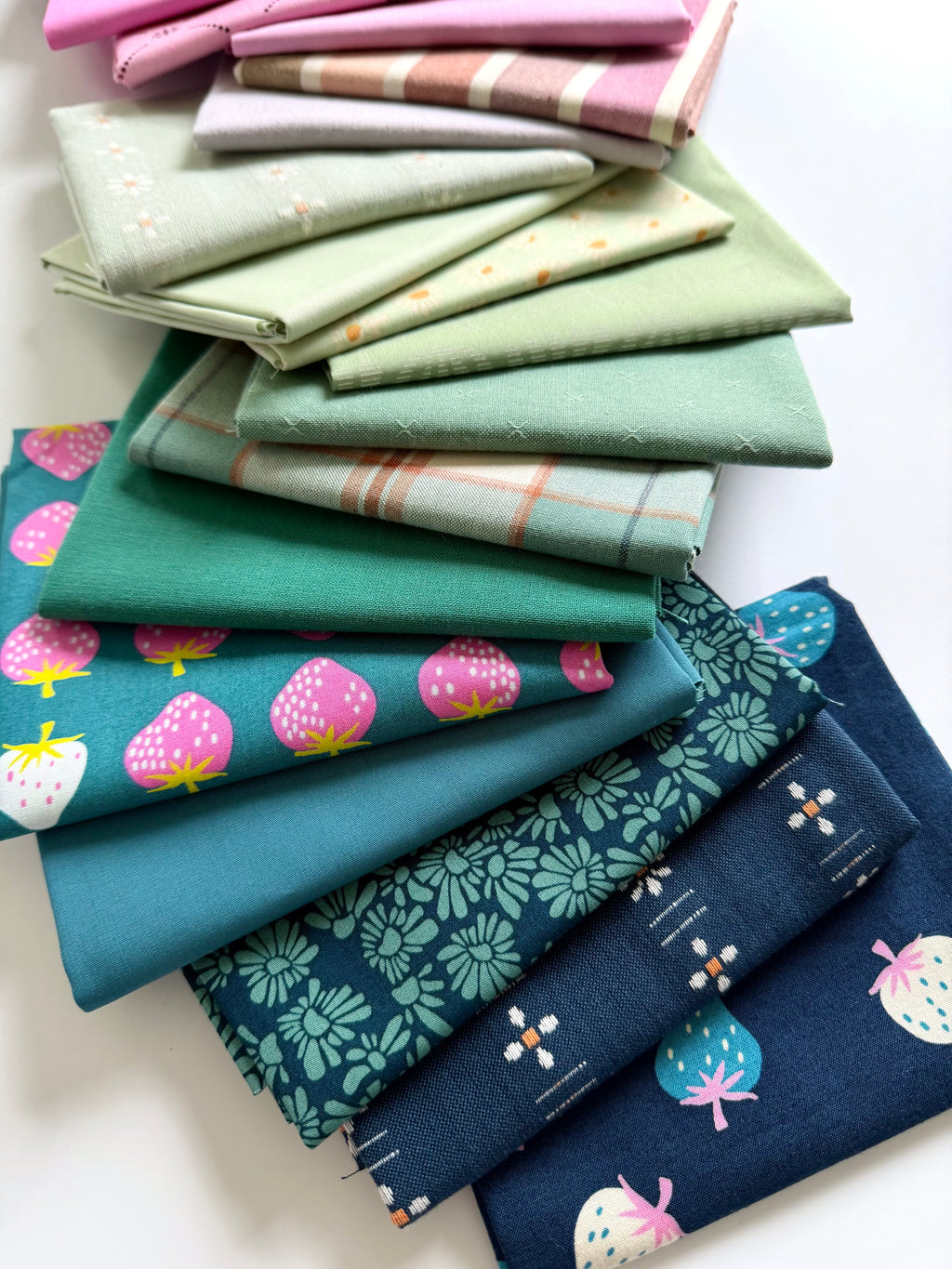 Collection of folded fabric swatches in various patterns and colors on a white background