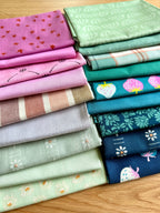 Stack of colorful folded fabrics with various patterns on a wooden surface