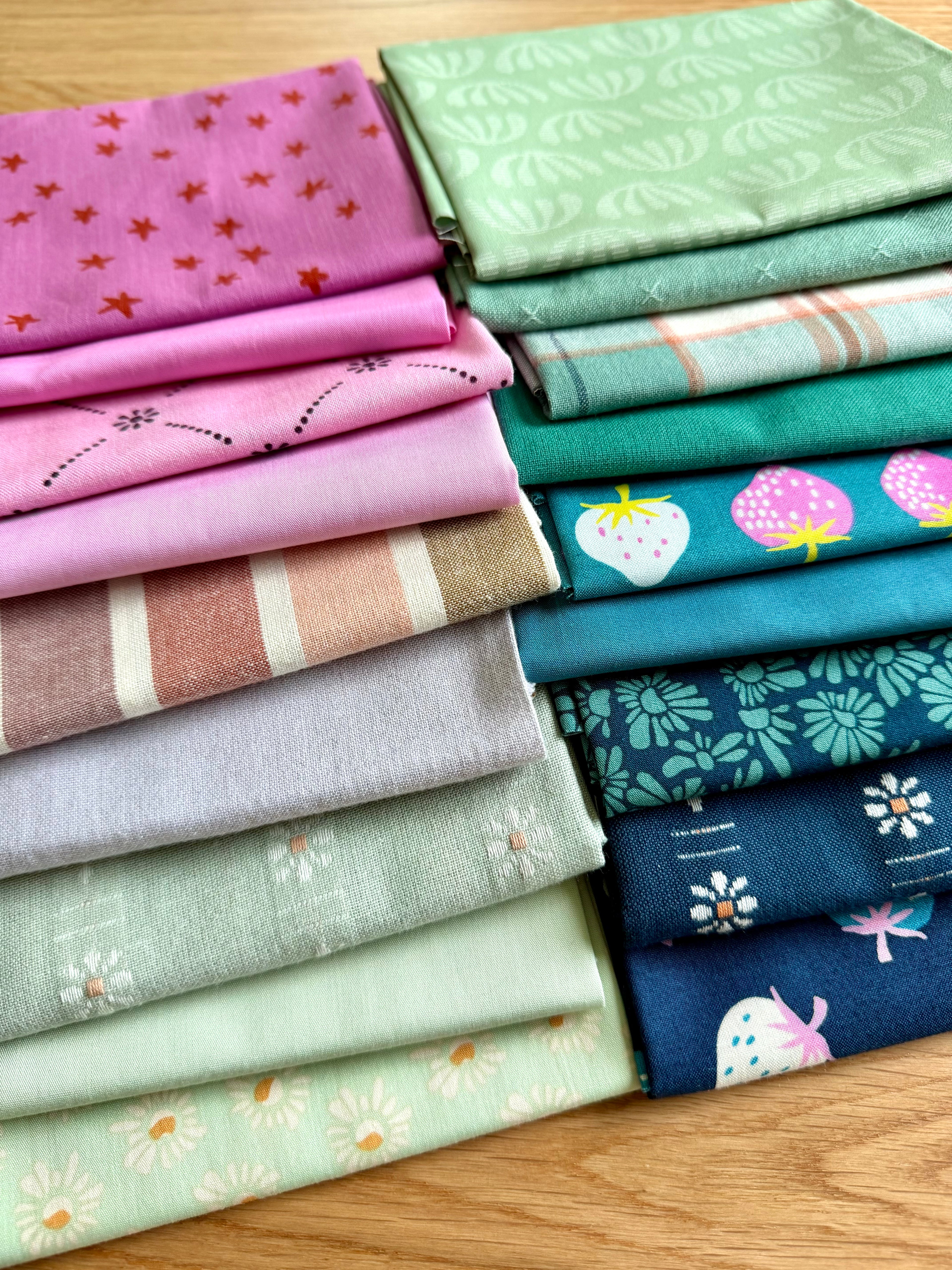 Stack of colorful folded fabrics with various patterns on a wooden surface