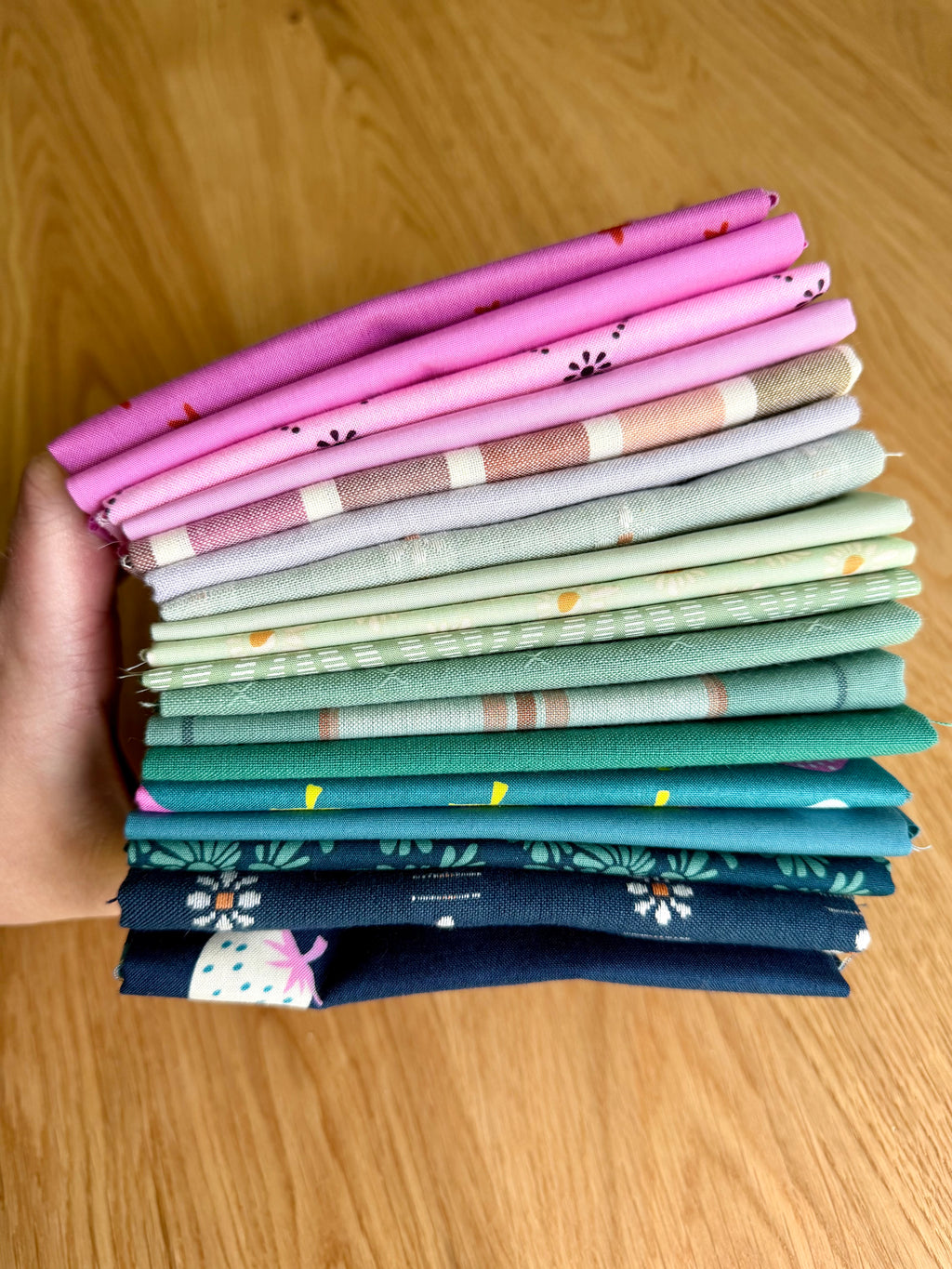Stack of colorful fabric swatches held by a hand on a wooden surface