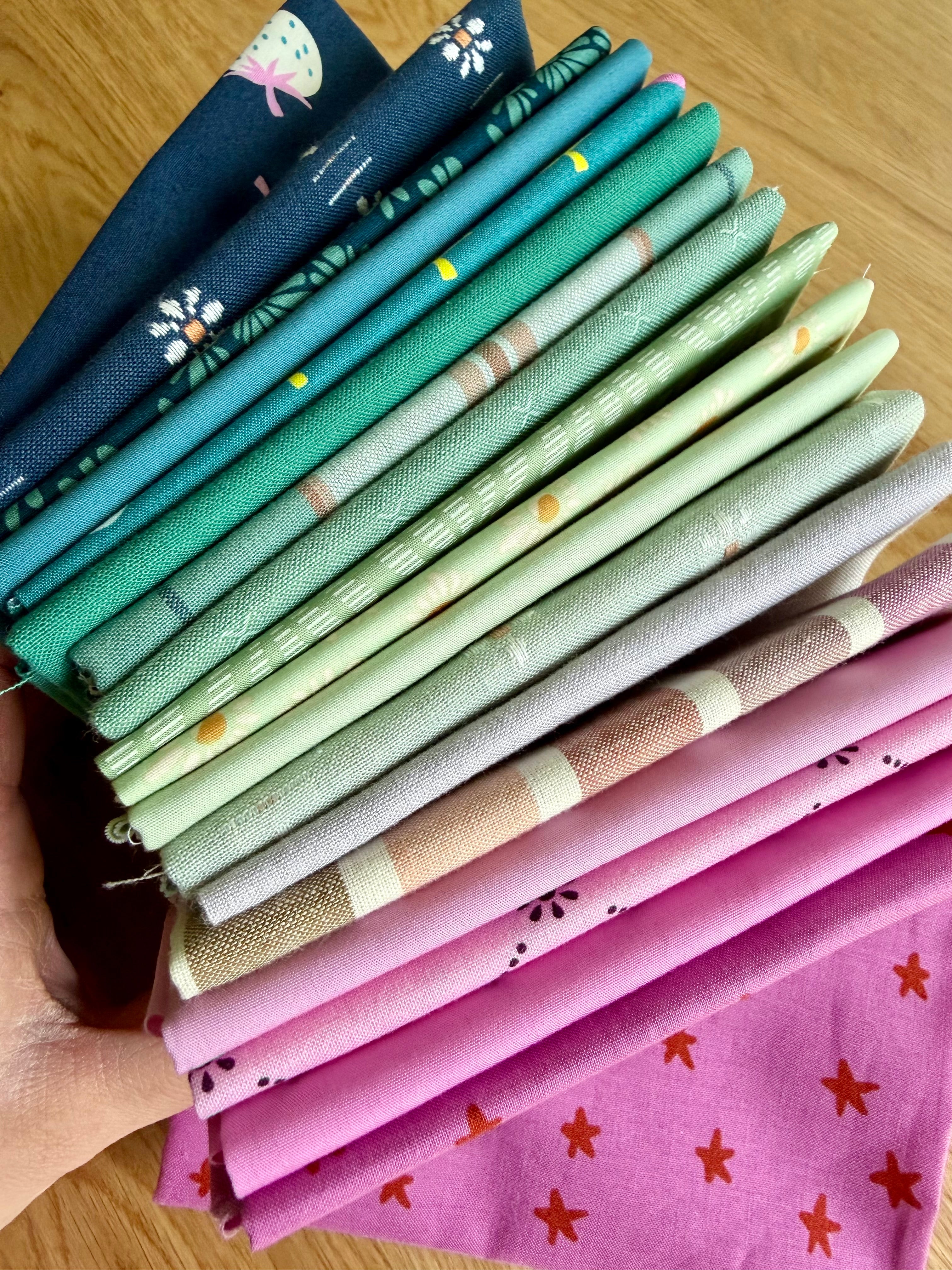 Stack of colorful fabric strips held by a hand on a wooden surface