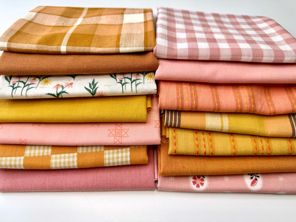A curated stack of 14 high-quality fabric quarters from the Golden Hour Glow bundle. The mix features rich mustard yellow, deep terracotta rust, soft blush pink, cream, and warm neutral fabrics. The collection showcases a blend of textures and patterns, including yarn-dyed wovens, classic ginghams, windowpane plaids, delicate stripes, and a central floral botanical print, styled flat on a clean white background.