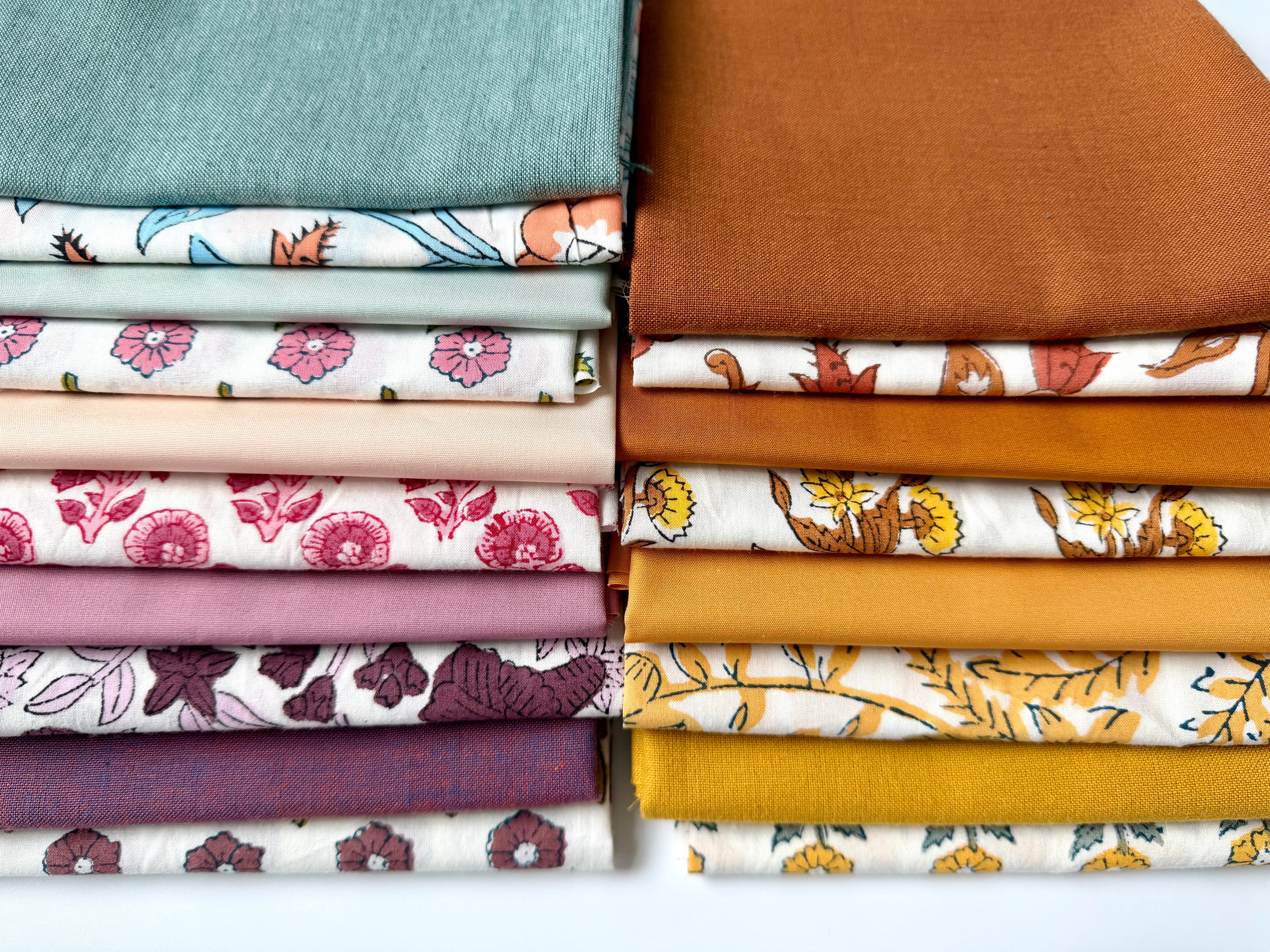 Stack of colorful fabric swatches with various patterns on a white background