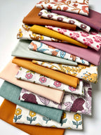 Stack of colorful fabric swatches with floral patterns on a white background