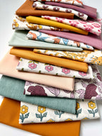 Stack of colorful fabric swatches with floral and solid patterns on a white background