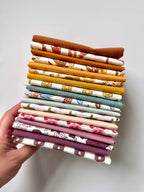 Stack of colorful fabric strips held by a hand on a light background