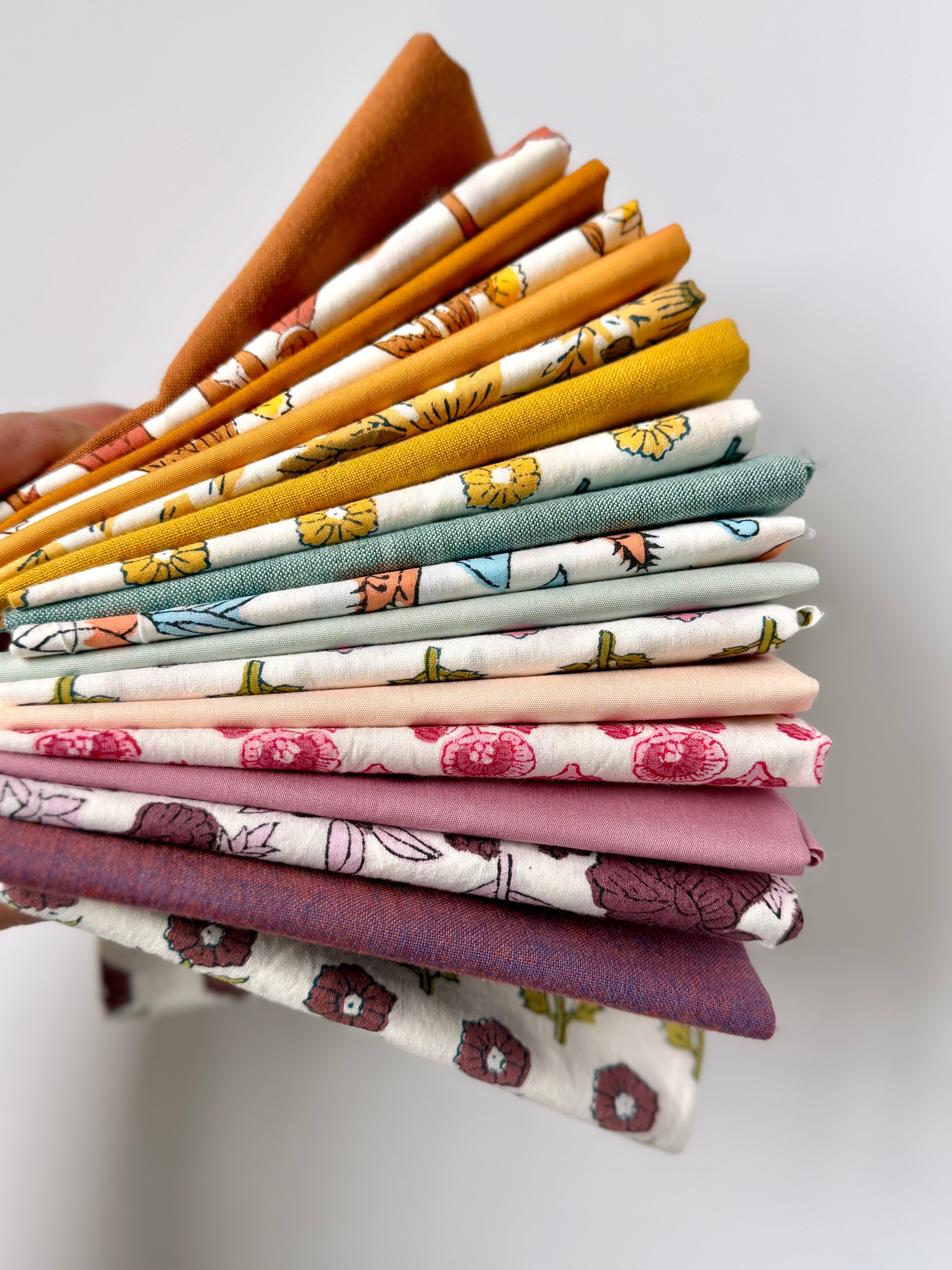 Stack of colorful fabric swatches held by a hand on a light background