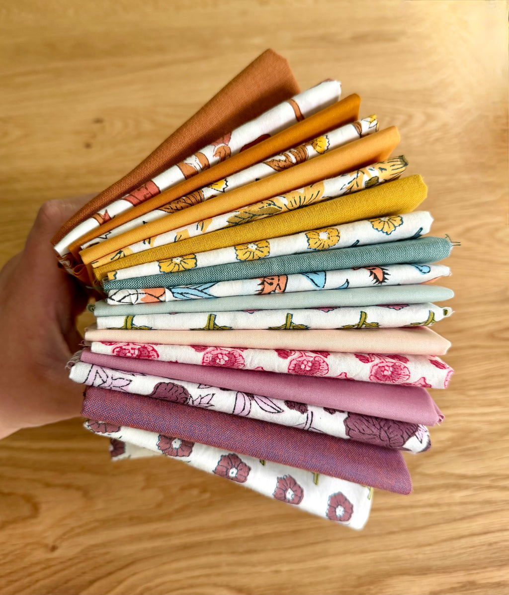 Stack of colorful fabric swatches held by a hand on a wooden surface