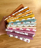 Stack of colorful fabric swatches held by a hand on a wooden surface