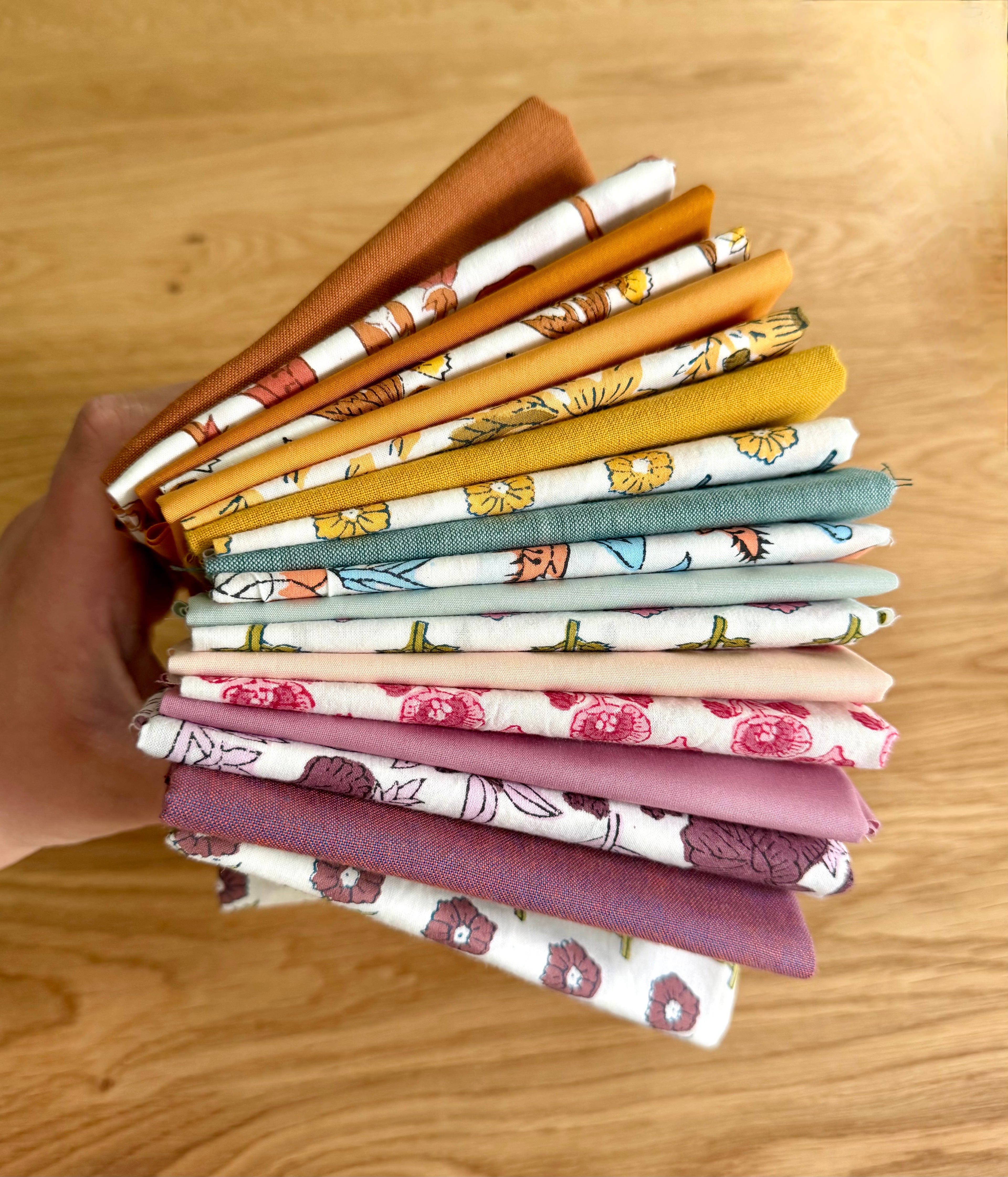Stack of colorful fabric swatches held by a hand on a wooden surface