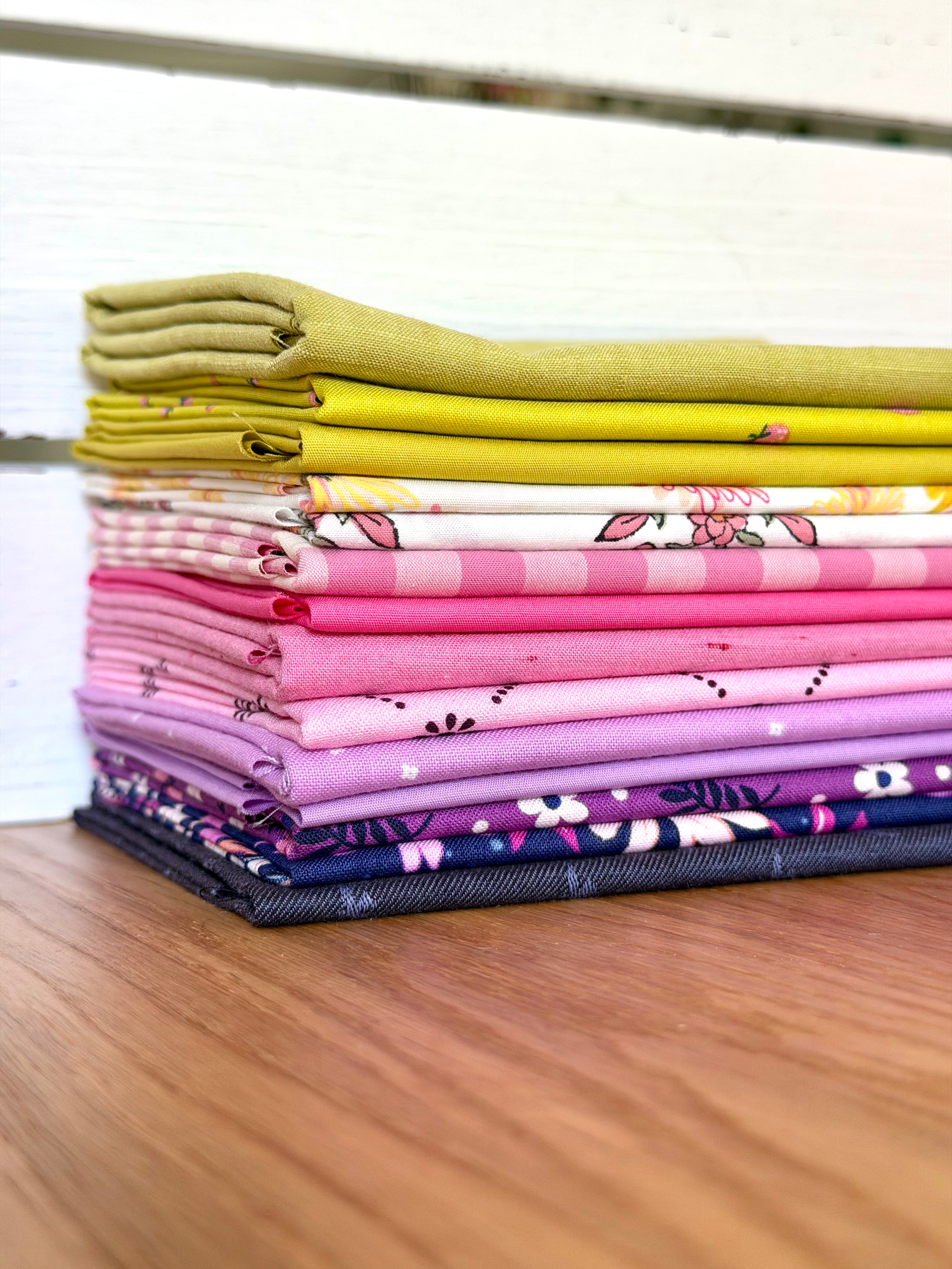 Stack of colorful fabric neatly folded on a wooden surface against a white background