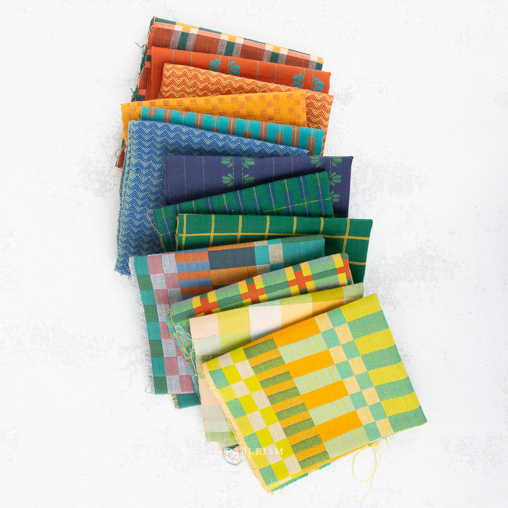 A stack of colorful patterned fabric squares fanned out on a white background. The fabrics feature various plaid, stripe, and geometric patterns in shades of green, yellow, orange, blue, pink, and purple.