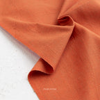 Close-up of orange fabric with 'Fableism' branding on a white background